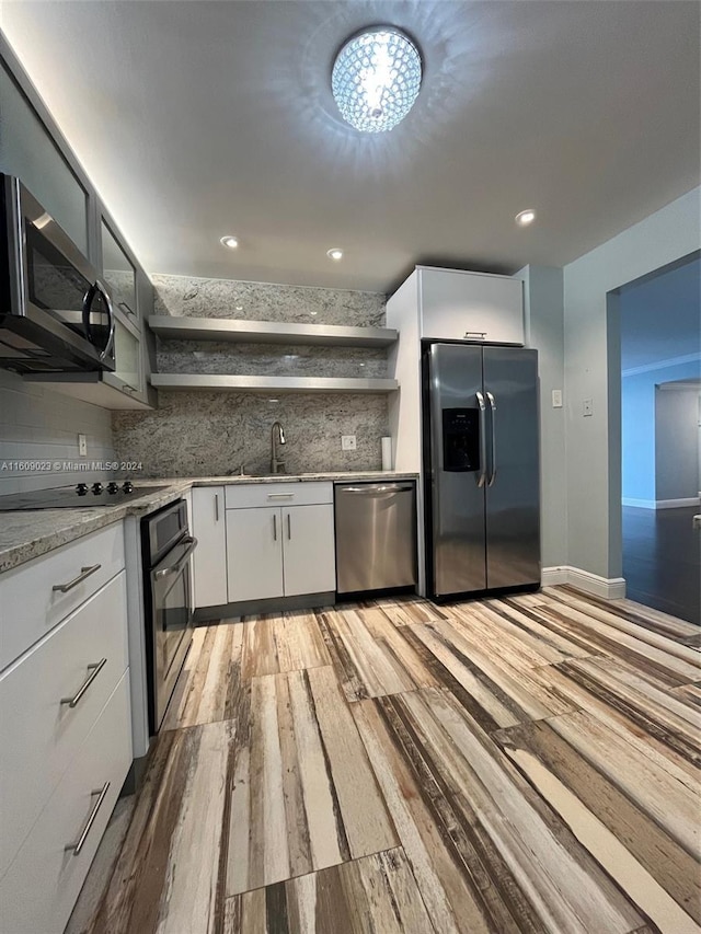 kitchen featuring white cabinets, appliances with stainless steel finishes, light wood-type flooring, and decorative backsplash