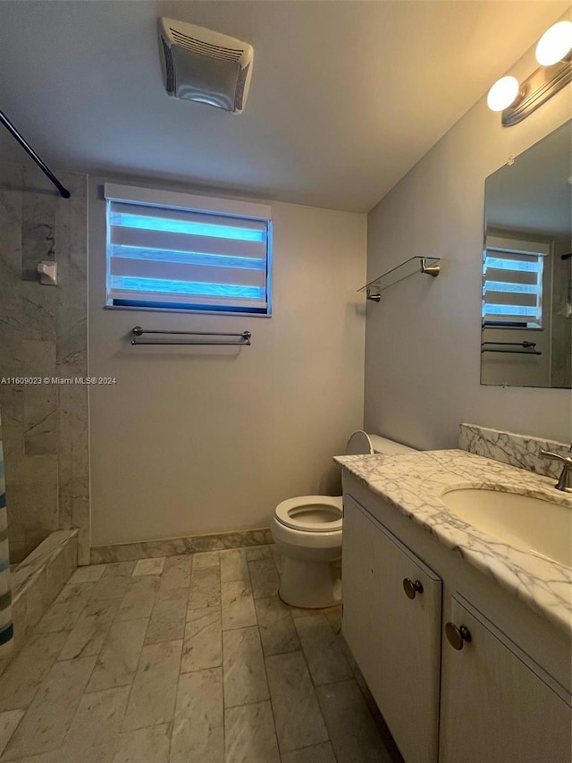 bathroom with vanity, a tile shower, and toilet