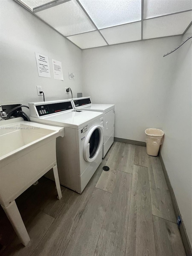 clothes washing area with separate washer and dryer and light hardwood / wood-style flooring