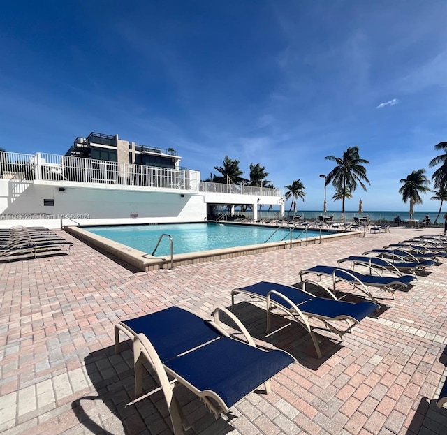 view of swimming pool featuring a water view and a patio