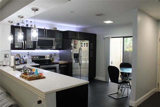 kitchen with kitchen peninsula, hanging light fixtures, stainless steel appliances, and sink