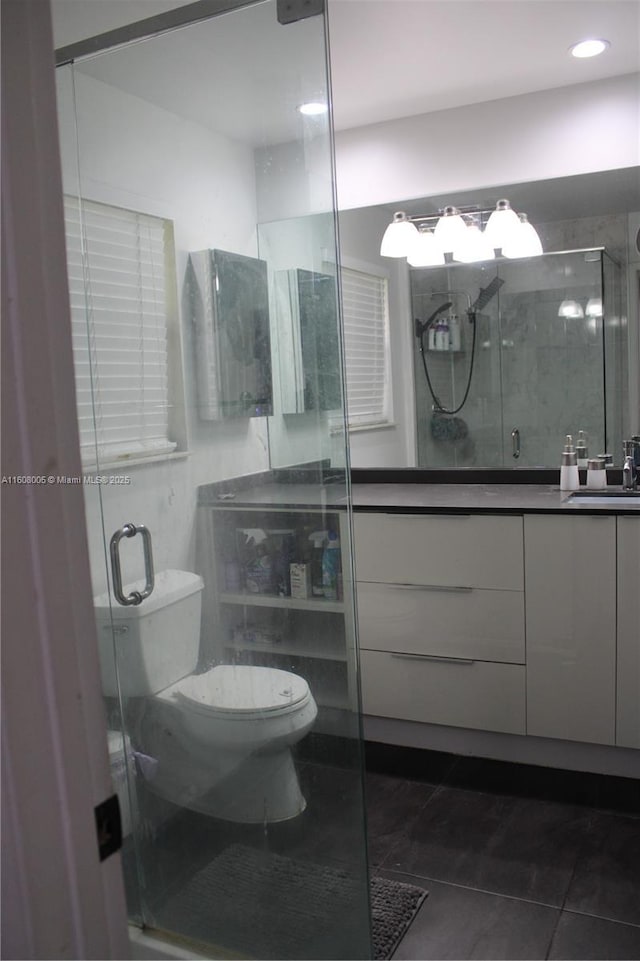 bathroom featuring tile patterned flooring, vanity, a shower with door, and toilet