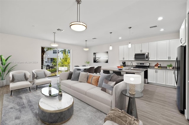 living room featuring sink and light hardwood / wood-style floors