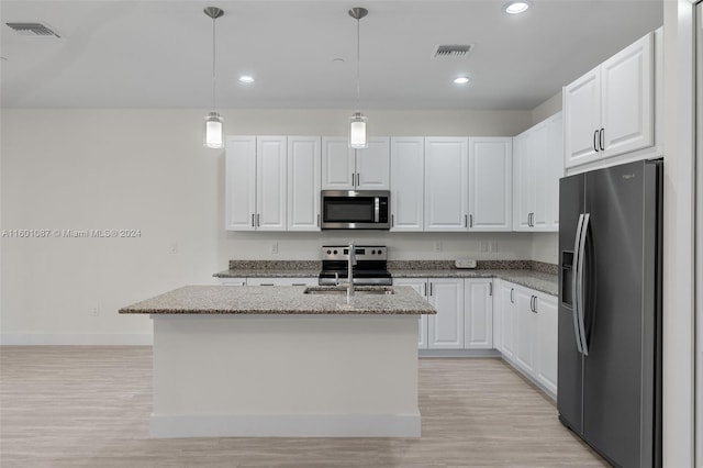 kitchen featuring white cabinets, pendant lighting, appliances with stainless steel finishes, and an island with sink