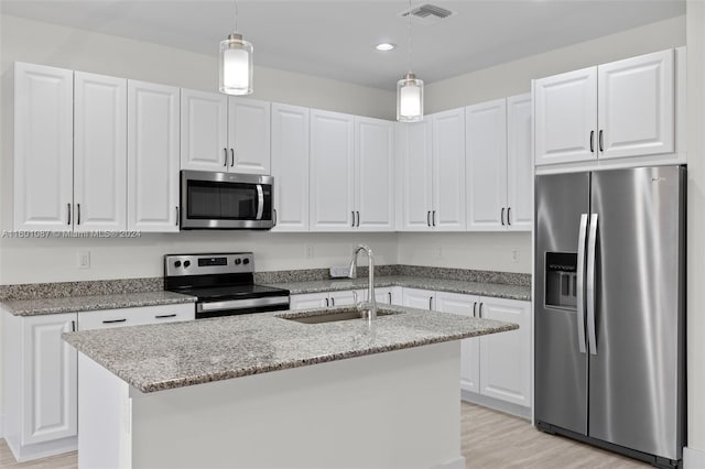 kitchen featuring appliances with stainless steel finishes, pendant lighting, white cabinets, and sink