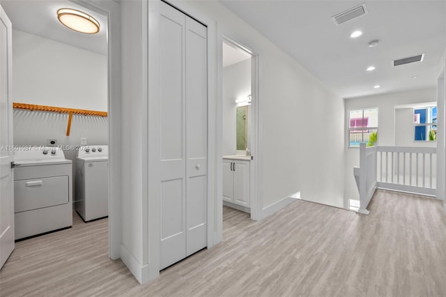 washroom with washer and clothes dryer, light hardwood / wood-style flooring, and sink