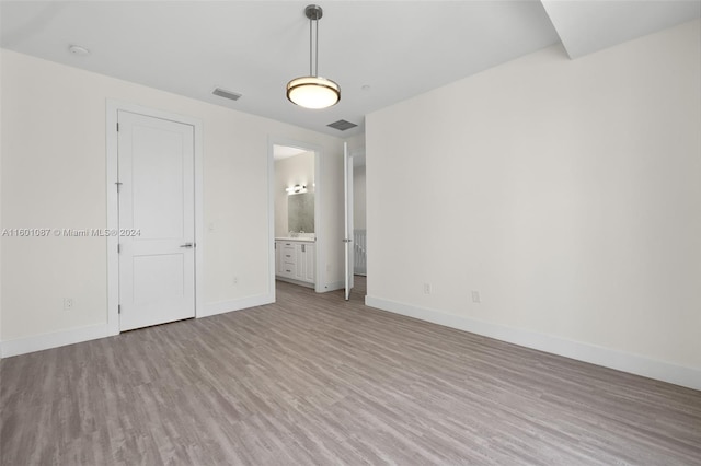 unfurnished bedroom featuring light hardwood / wood-style floors and ensuite bath