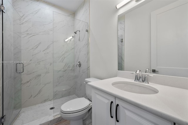 bathroom with toilet, vanity, and a shower with shower door