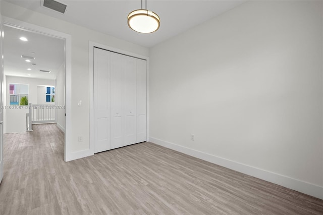 unfurnished bedroom featuring a closet and light hardwood / wood-style floors