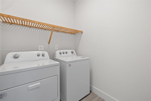 clothes washing area featuring light wood-type flooring and washer and clothes dryer