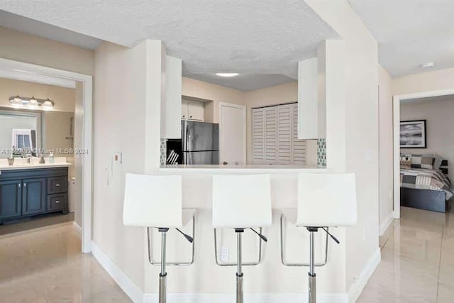 kitchen with a textured ceiling, stainless steel fridge, and blue cabinetry