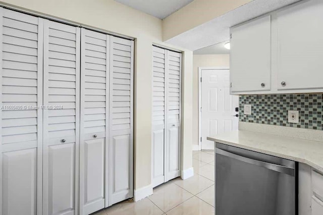 kitchen with backsplash, white cabinets, light tile patterned floors, and stainless steel dishwasher