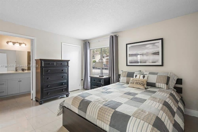 tiled bedroom featuring ensuite bath and a textured ceiling