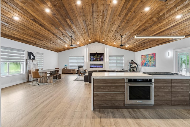 kitchen with appliances with stainless steel finishes, a wealth of natural light, light wood-type flooring, and wooden ceiling