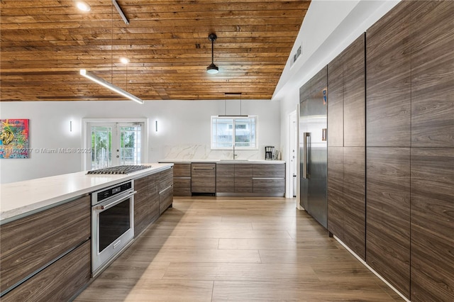 kitchen with lofted ceiling, hanging light fixtures, stainless steel appliances, wooden ceiling, and light hardwood / wood-style flooring