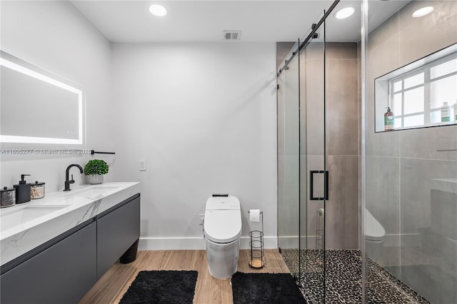 bathroom with hardwood / wood-style flooring, vanity, toilet, and a shower with door