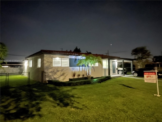 back house at twilight featuring a lawn