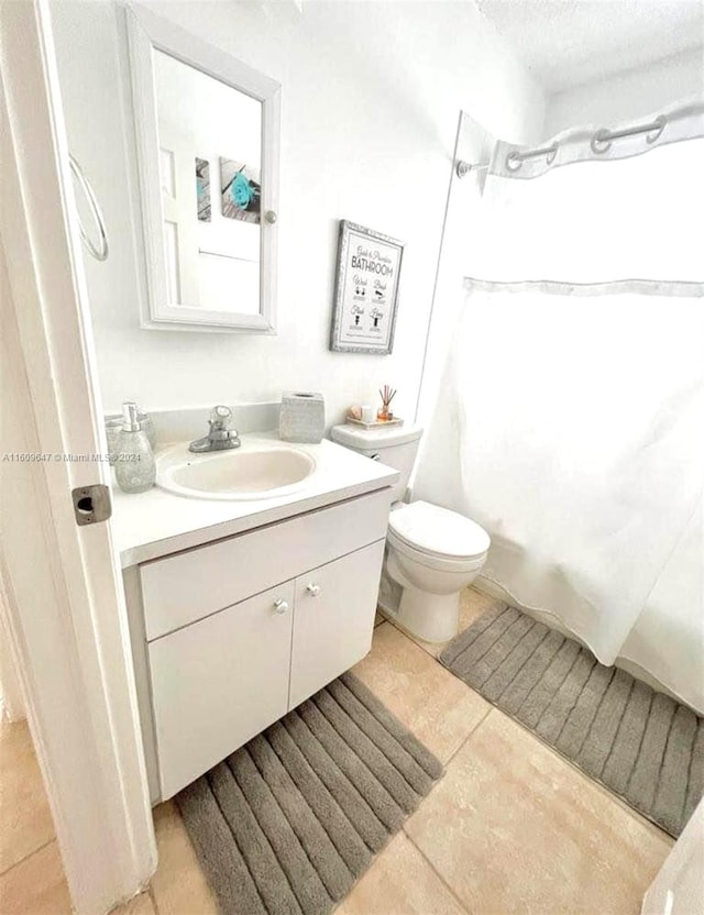 bathroom featuring vanity, a textured ceiling, toilet, and tile patterned floors