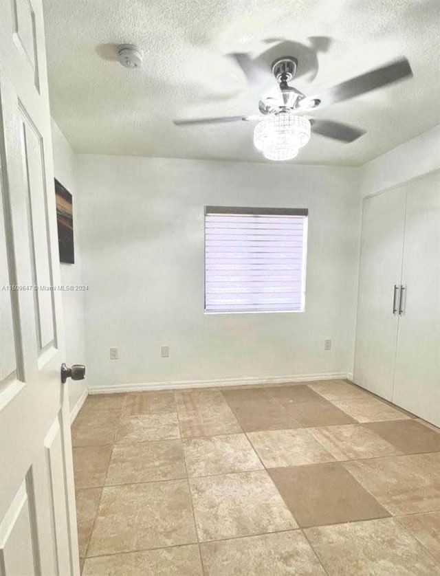 tiled spare room with a textured ceiling and ceiling fan