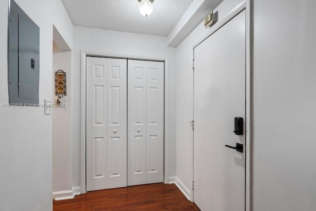 hall with a textured ceiling, dark hardwood / wood-style floors, and electric panel