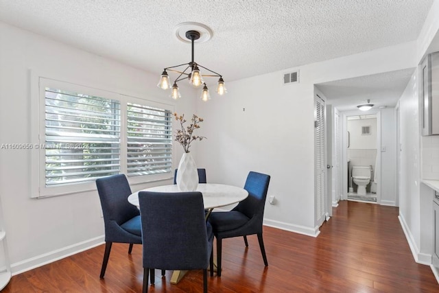 dining room featuring a textured ceiling, dark hardwood / wood-style floors, and a chandelier