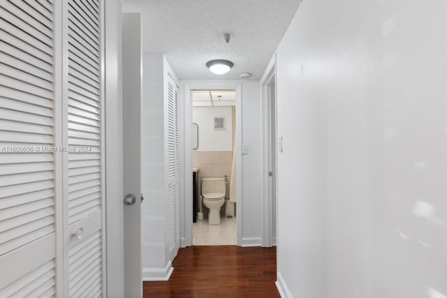 corridor with a textured ceiling and dark hardwood / wood-style floors