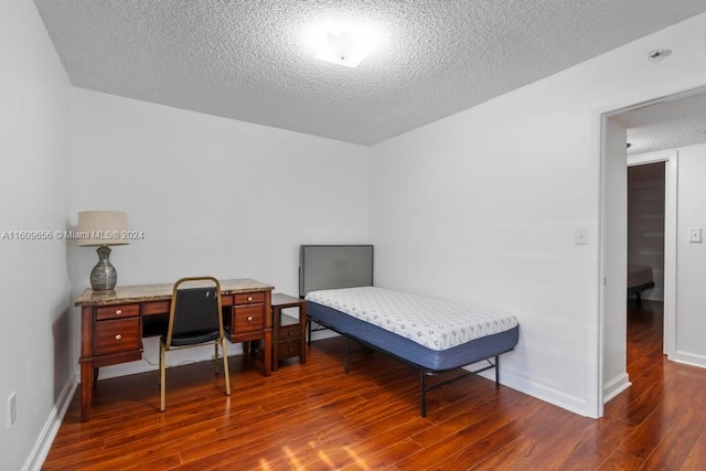 bedroom with a textured ceiling and dark hardwood / wood-style flooring