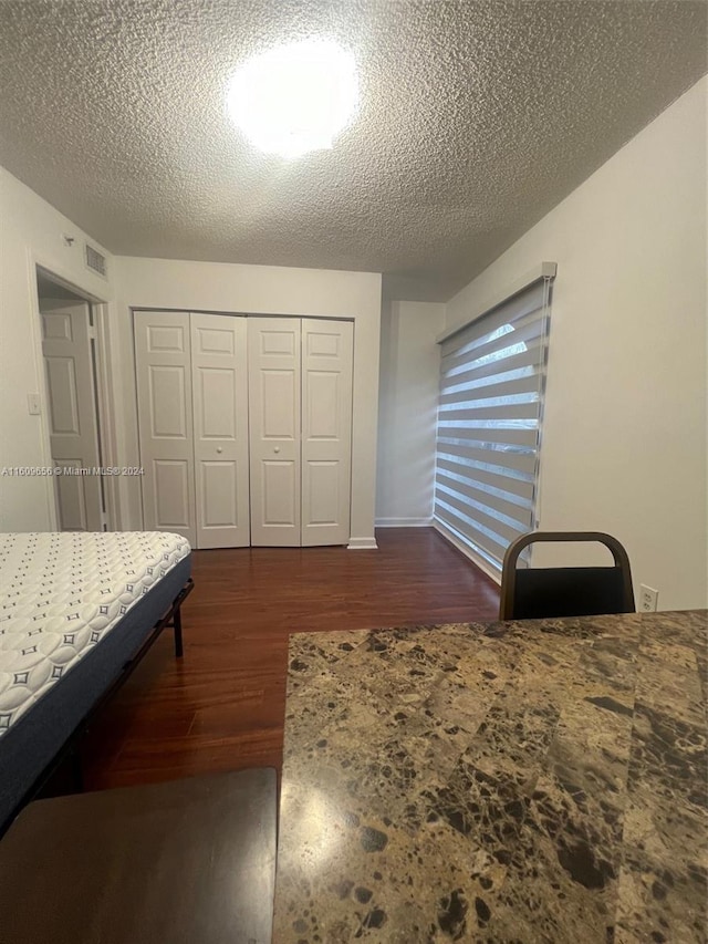 bedroom with a textured ceiling, a closet, and dark hardwood / wood-style floors