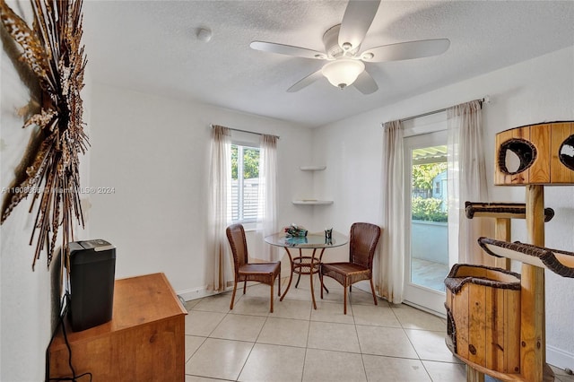 living area with a textured ceiling, ceiling fan, and light tile patterned floors