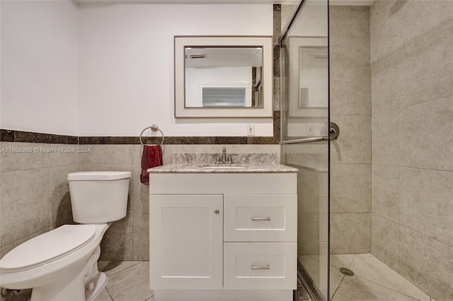 bathroom with toilet, tile walls, a shower with shower door, and vanity