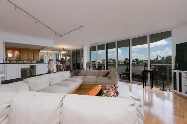 living room with an inviting chandelier, a wall of windows, and light hardwood / wood-style flooring