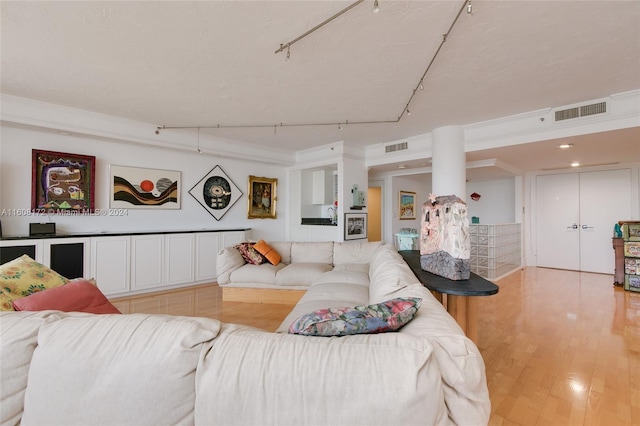 living room with rail lighting, ornamental molding, and light hardwood / wood-style flooring