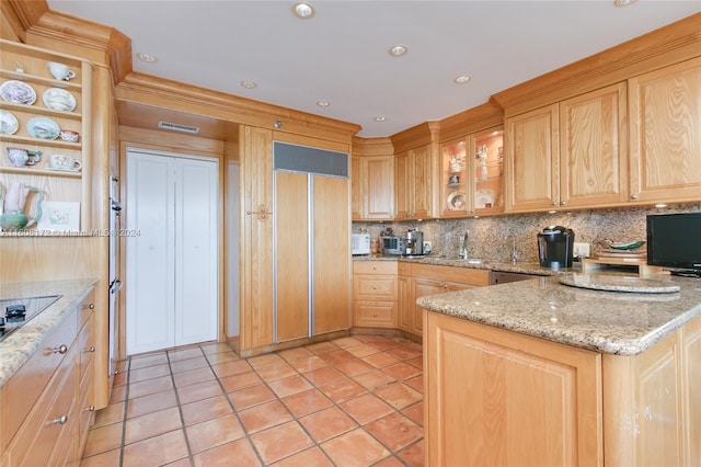 kitchen with light tile patterned flooring, tasteful backsplash, paneled built in fridge, light stone countertops, and black electric cooktop