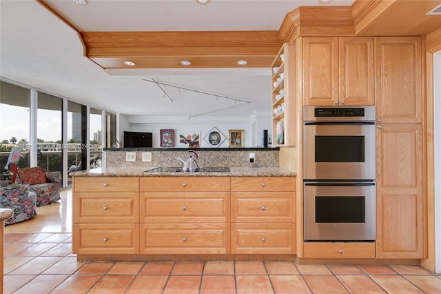 kitchen with sink, light stone countertops, expansive windows, and stainless steel double oven