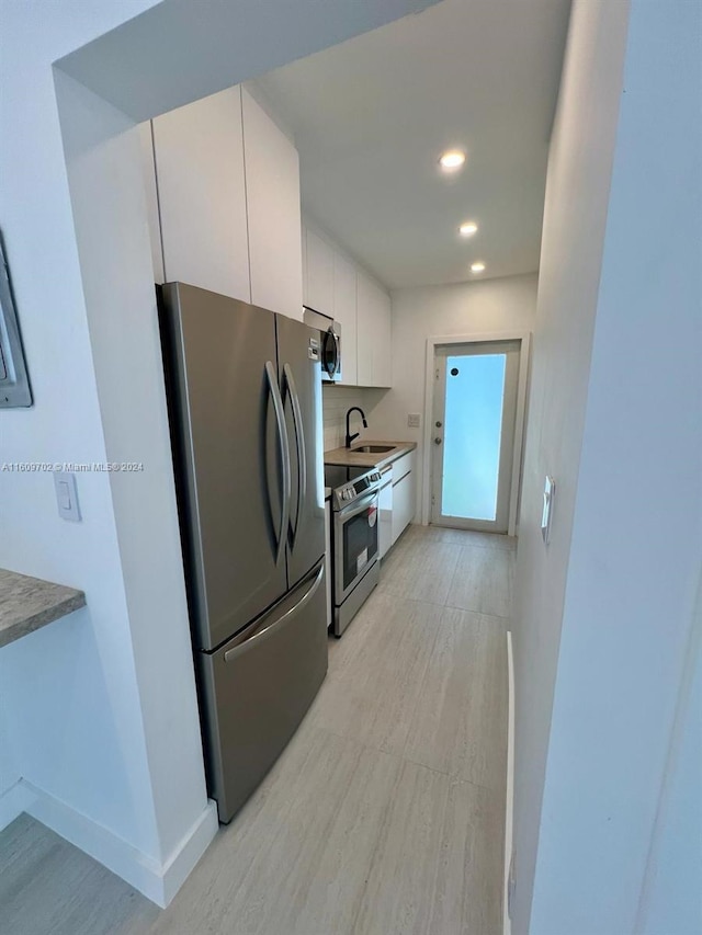 kitchen featuring sink, white cabinets, backsplash, and appliances with stainless steel finishes