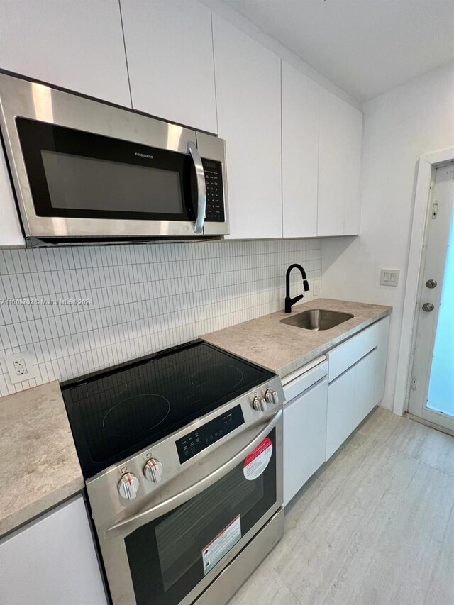 kitchen featuring white cabinets, sink, tasteful backsplash, and stainless steel appliances