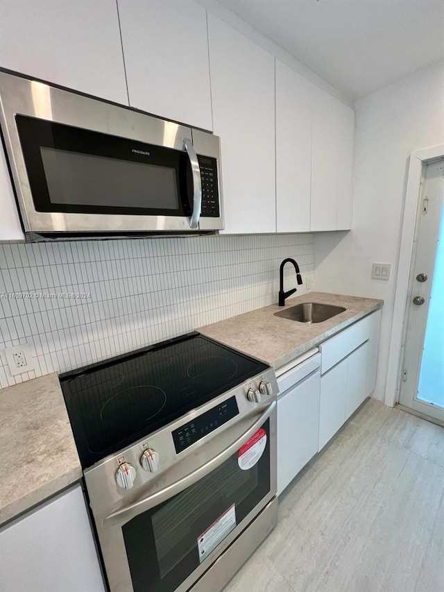 kitchen featuring tasteful backsplash, sink, white cabinets, and appliances with stainless steel finishes