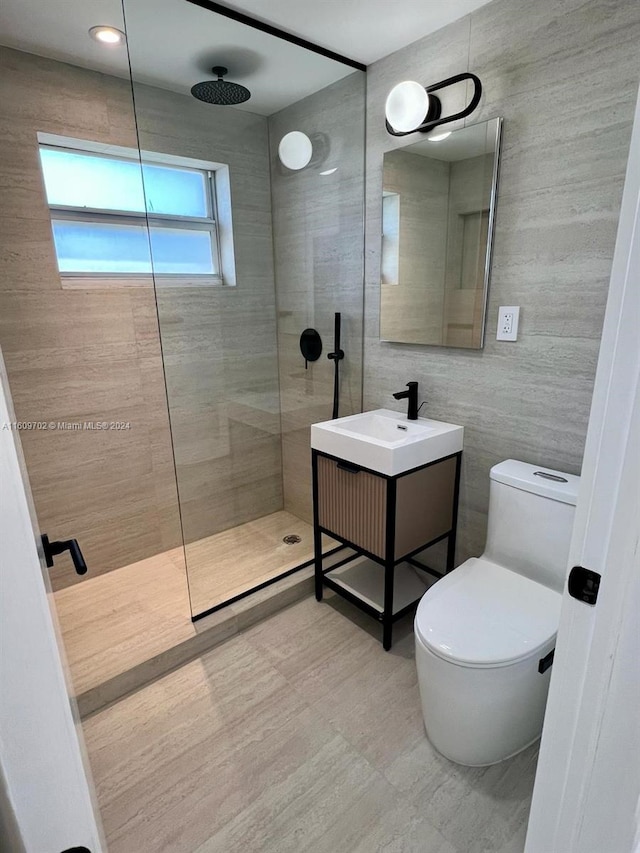 bathroom featuring tiled shower, tile walls, vanity with extensive cabinet space, toilet, and tile flooring