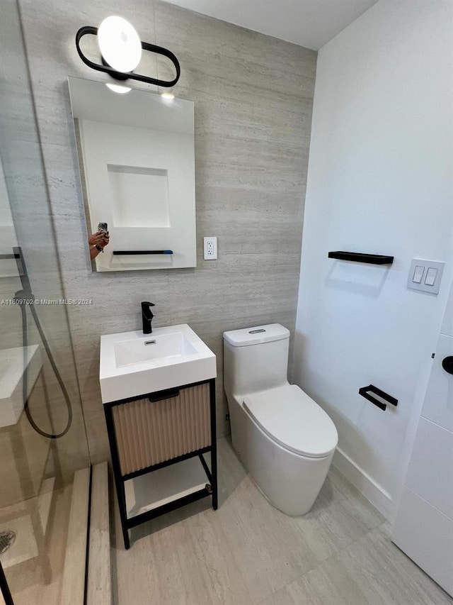 bathroom featuring vanity, a shower, tile walls, and toilet