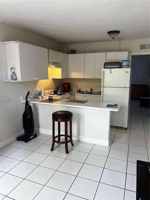 kitchen featuring white cabinetry, white fridge, light tile flooring, and kitchen peninsula