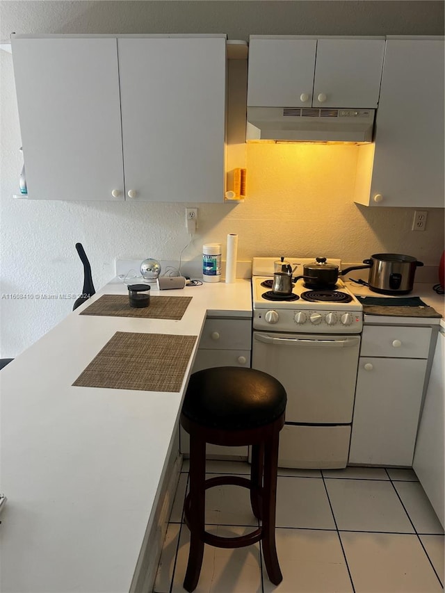 kitchen with a kitchen breakfast bar, white range oven, and light tile floors