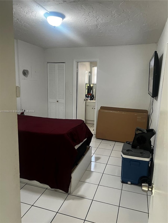 tiled bedroom with a closet, a textured ceiling, and ensuite bath