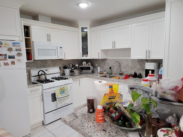 kitchen featuring tasteful backsplash, white appliances, light tile floors, sink, and white cabinets