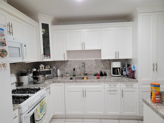 kitchen featuring white appliances, light stone counters, backsplash, sink, and white cabinetry