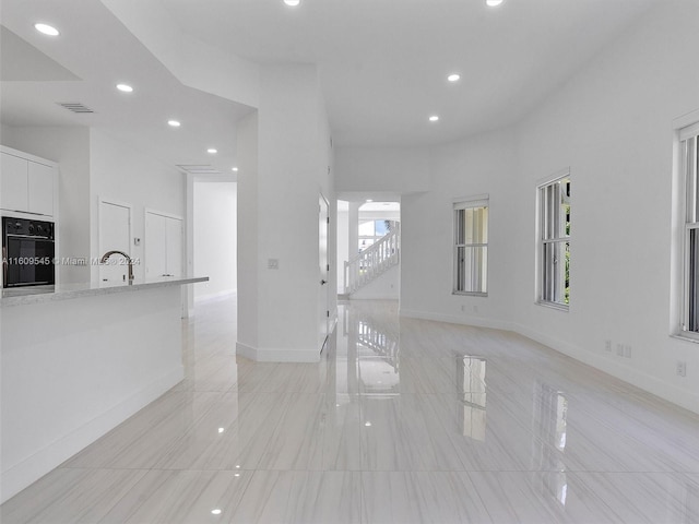 unfurnished living room featuring sink and light tile flooring