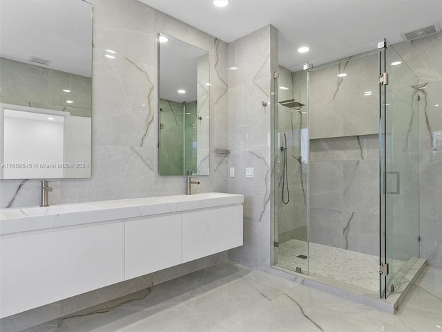 bathroom with tile floors, a shower with door, double vanity, and tile walls