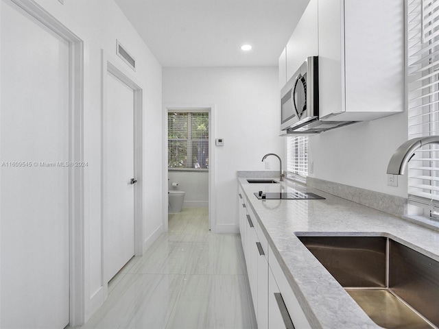 kitchen featuring sink, white cabinets, and light tile floors