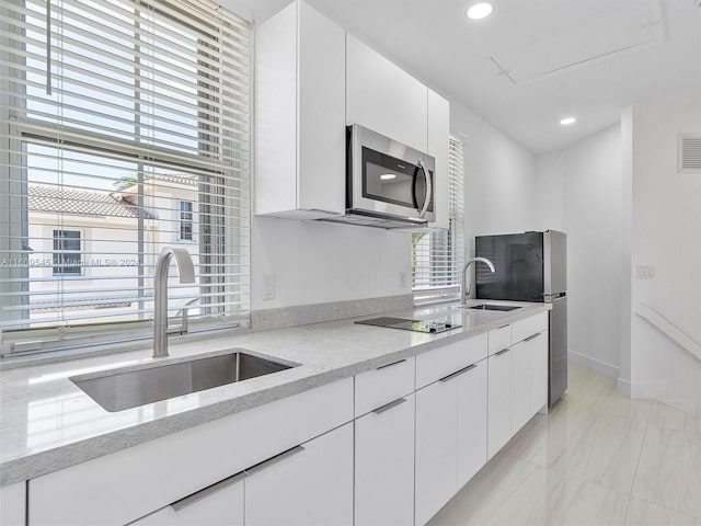 kitchen featuring appliances with stainless steel finishes, sink, white cabinets, and a healthy amount of sunlight