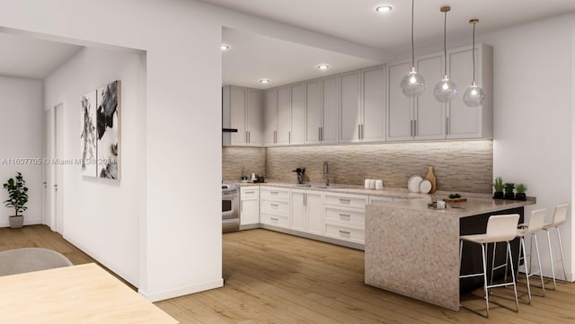 kitchen featuring stainless steel stove, decorative light fixtures, tasteful backsplash, sink, and kitchen peninsula