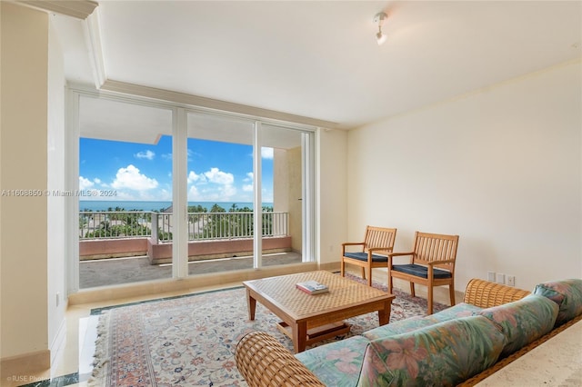 tiled living room featuring a water view and a wall of windows